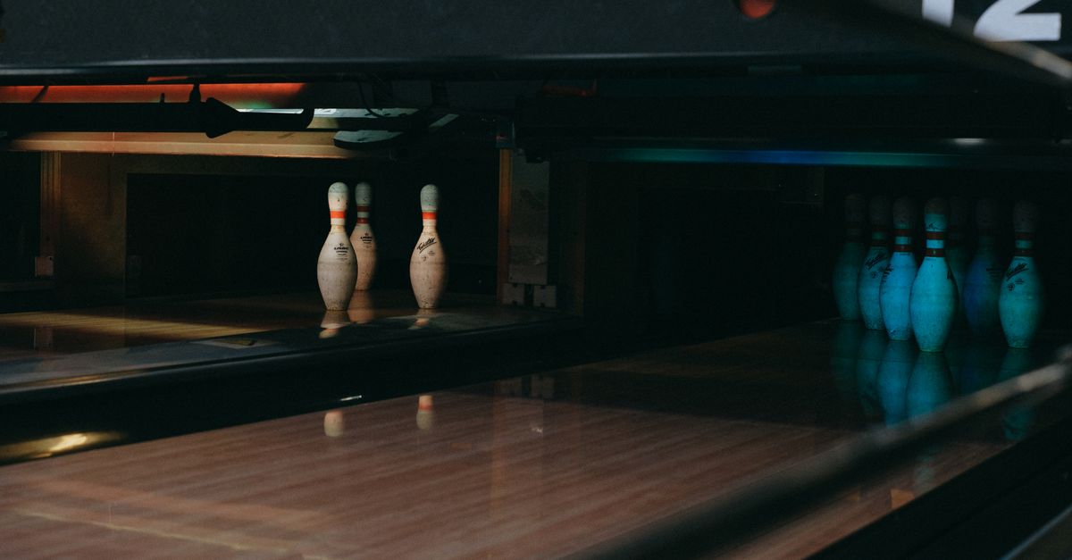 A dimly lit bowling alley showcasing lined-up pins ready for a strike.